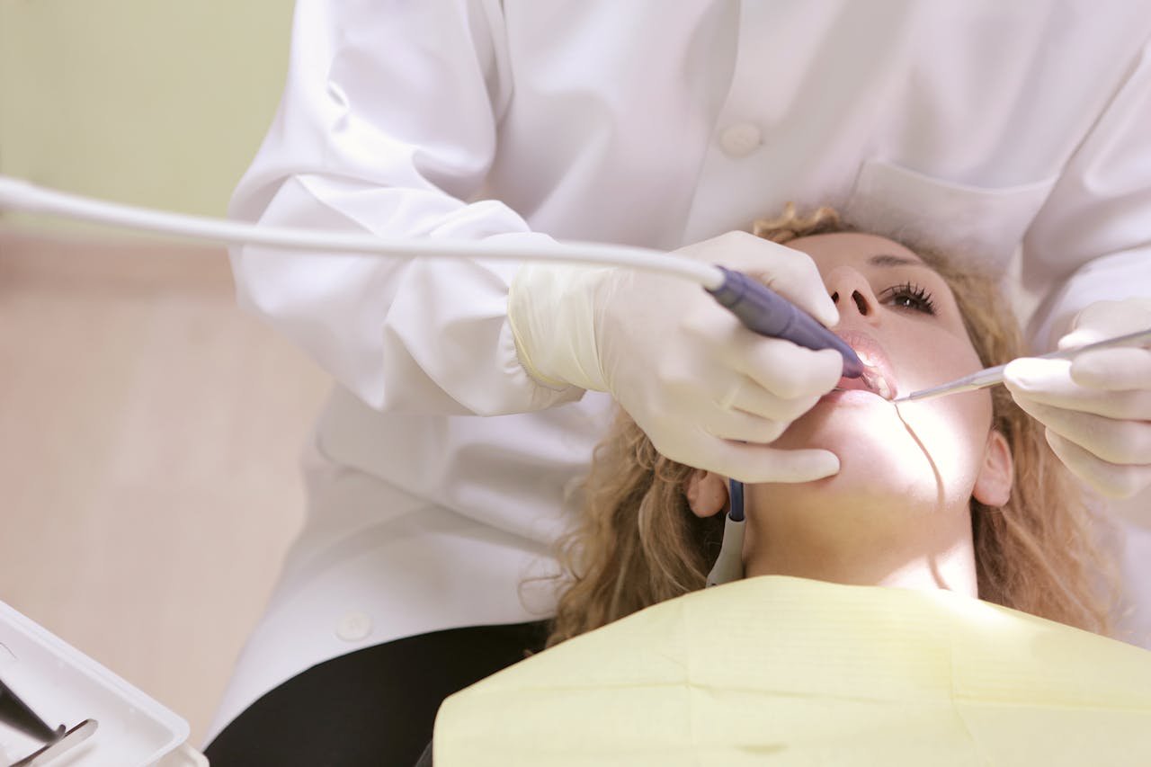 Dentiste en train de soigner les dents d'une patiente installée au fauteuil
